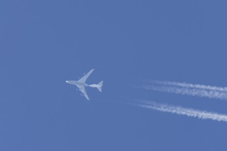 Boeing 747 jumbo jet cargo aircraft flying in a blue sky with contrails or vapour trails behind,
