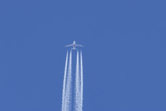 Airbus A380 jet passenger aircraft of Emirates airlines flying in a blue sky with contrails or