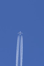 Airbus A380 jet passenger aircraft of Emirates airlines flying in a blue sky with contrails or