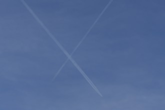 Aircraft contrails or vapour trails crossing in a blue sky, England, United Kingdom