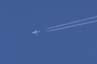 Airbus jet passenger aircraft flying in a blue sky with contrails or vapour trails behind, England,