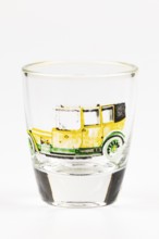 Shot glass with historic car motif, mainly in yellow