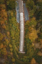 Aerial view of a partly covered railway tunnel surrounded by colorful trees, Hermann-Hesse-Bahn
