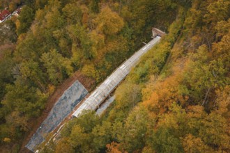 Aerial view of a railway tunnel under construction between autumnal forests, Hermann-Hesse-Bahn