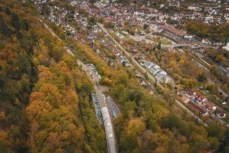 Aerial view of a city next to an autumnal forest landscape with train tunnel, Hermann-Hesse-Bahn