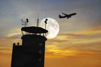 Air traffic control tower at airport as airplane takes off