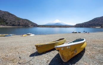 Rowing boats on shore, view across the lake to Mt Fuji volcano, Motosu Lake, Yamanashi Prefecture,