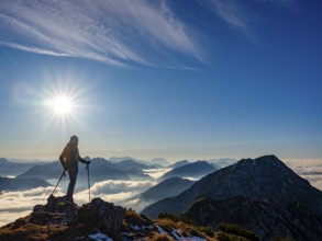 Mountaineer looking at blue-colored silhouette of mountains, fog in the valley, Hochstaufen,