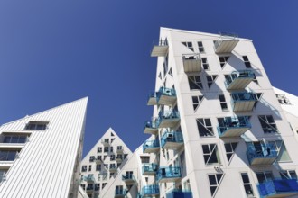 Distinctive white residential complex, turquoise balconies against blue sky, pyramid-shaped