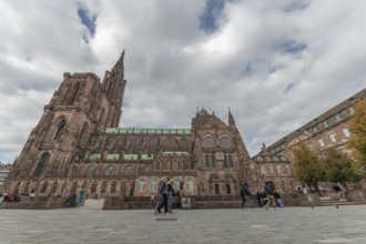 People walk in front of the majestic Strasbourg Cathedral, which is surrounded by historic