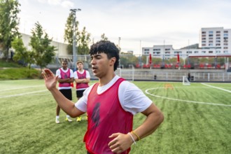 Soccer coach providing instructions to a group of young men in red bibs during a training session