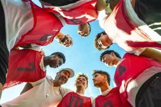 Coach and young diverse male soccer players forming a huddle, discussing strategy and fostering