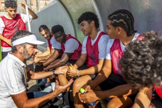 Soccer coach giving instructions and discussing tactics with his diverse young team of players
