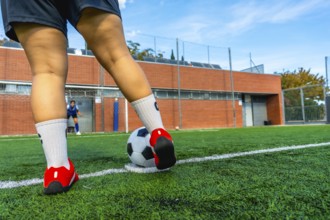 Woman soccer player preparing to strike a penalty kick on a green artificial turf field, with a