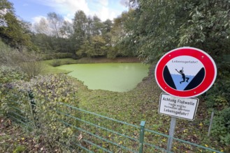 Fence with warning sign with lettering Danger to life and symbolic depiction of person falling into