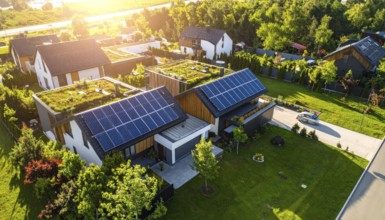 Aerial view showcases modern houses with solar panels and green roofs in a suburban setting,