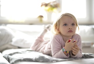Child, girl, 4 years, blonde, lying on sofa, watching TV, watching television, watching television,