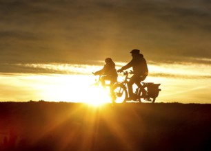 Cyclists ride on a cycle path on the island of Fehmarn at sunset, 13.10.2025, Fehmarn,