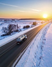Petrol cargo truck lorry tanker driving on highway hauling oil products at sunrise, wide snowy