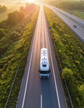 Petrol cargo truck lorry tanker driving on highway hauling oil products at sunrise, wide hilly