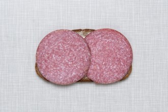 Top shot of a slice of bread smeared with margarine and topped with salami on a white Resopal plate