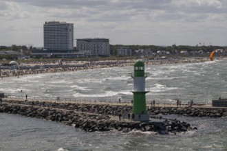 Green and white lighthouse, pier light Westmole in front of lively beach and hotels in the