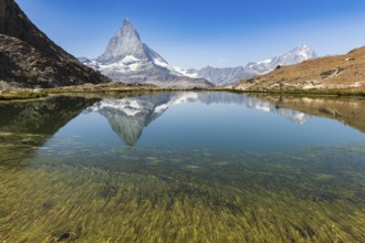The sharp peak of Matterhorn rises majestically above a serene alpine lake, reflecting perfectly on