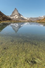 The sharp peak of Matterhorn rises majestically above a serene alpine lake, reflecting perfectly on