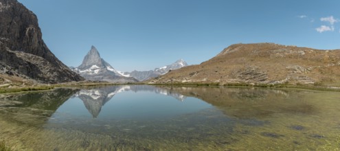 The snow-capped mountains rise majestically above a calm lake, where their towering reflections