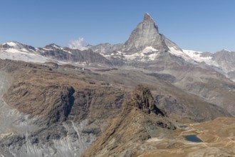 The towering peak of the Matterhorn dominates the clear sky, surrounded by rocky terrain and