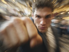A man shows an outstretched fist to the camera while the background blurs into motion, symbolic
