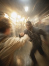 A man gets into a fighting stance, surrounded by dynamic movement and a background filled with