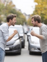 Two angry men arguing in the street, possibly triggered by a road traffic incident, symbolic image