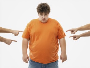 Overweight boy being judged by pointing fingers, symbolising fatshaming, bullying, judgement and