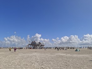 Wide North Sea beach with pile dwellings, blue sky, white clouds, summer, sun, beach chairs, on the