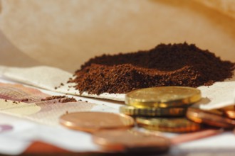 Ground coffee in a filter bag with coins and a ten euro note in front of it, North