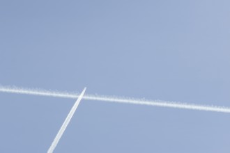 Jet passenger aircraft with a vapour trail or contrail flying in a blue sky, England, United