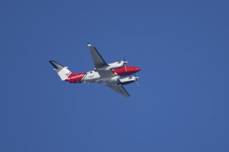 Beech King Air 350 light aircraft of the UK HM Coastguard flying in a blue sky, England, United