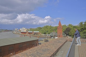 Tourist looking at the tower of the lift bridge and shed 8 at the Hansa harbour, Stadttrave,