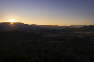 The sun sets behind the mountains on the Mediterranean island of Sardinia, Monte Nai, Costa Rei,