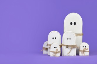 Cute wooden white Halloween ghost ornaments on purple background