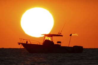 The sun rises behind a boat on the Costa Rei, a coastal stretch of the Italian Mediterranean island