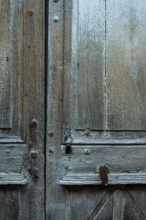 Weathered wooden doors exhibit intricate textures and aged details in an old building. The natural