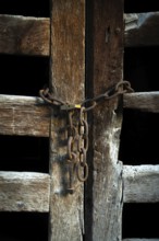 The wooden door, weathered and aged, is closed off with rusty chains, creating an intriguing
