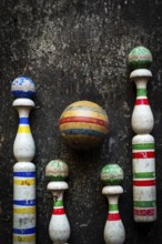 A classic bowling game set showcases worn wooden pins in vibrant colors and a striped ball,