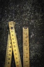 Two antique wooden rulers rest on a rough, dark surface, showcasing their intricate details and