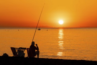 A man fishing shortly after sunrise on the Costa Rei, a stretch of coastline on the Italian island