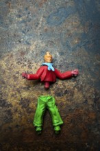 Brightly colored toy figure parts lie scattered on a rusted metal surface, showcasing a mix of red