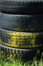 Tires are stacked on top of each other, featuring a vibrant yellow band. The background consists of