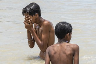 Children bathe in the Brahmaputra River to seek relief from the intense summer heat in Guwahati,
